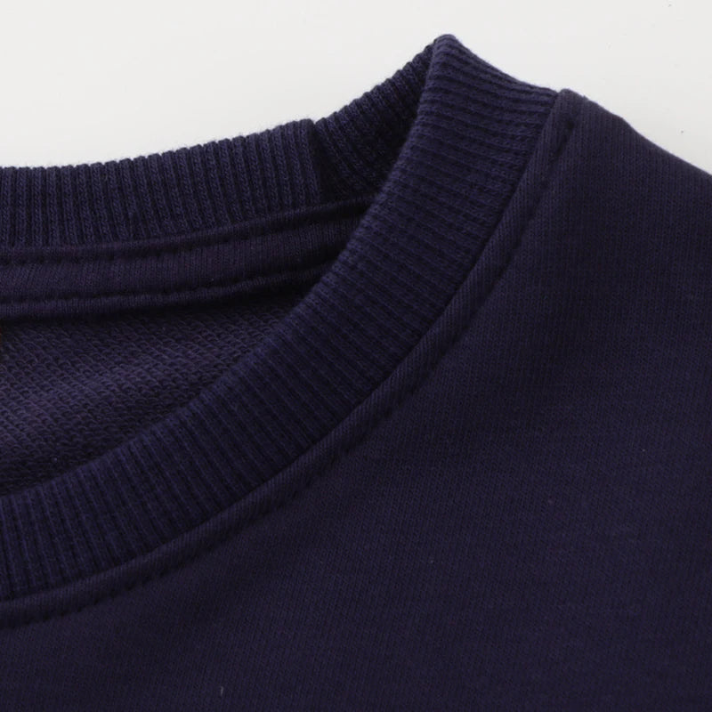 Close-up of the neckline of the Go Glow dinosaur sweater, showing the ribbed detailing on a dark fabric.