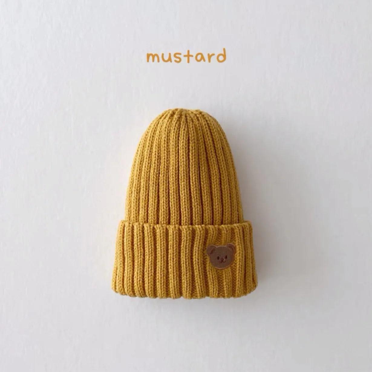 Little Tickle baby hat in mustard color, featuring a cute embroidered bear face on the front.